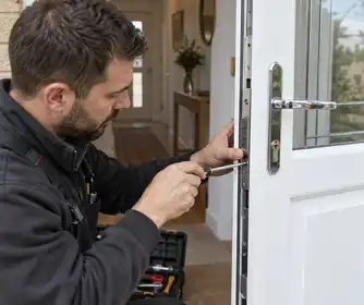 Illustrative Burglary uPVC Door Repairs scene: Locksmith repairs a white uPVC door.