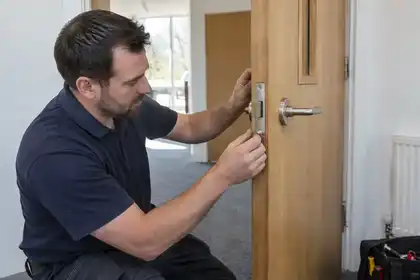 Locksmith inspecting latch alignment on solid timber fire door.