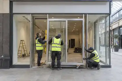 Installers fitting a glazed shop entrance in a retail arcade